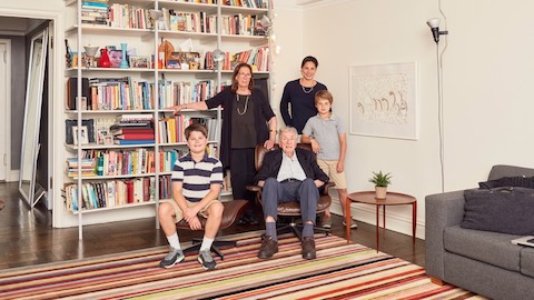 Five family members pose near a bookcase. Select to go to an article about one family's experience with an Eames Lounge Chair and Ottoman.