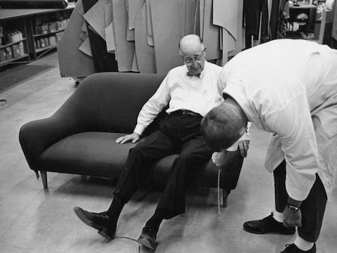 Herman Miller founder D.J. De Pree tries out a sofa while an employee takes measurements.