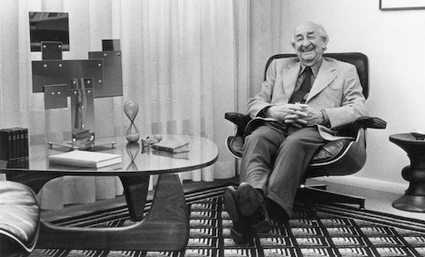 Herman Miller founder D.J. De Pree reclines in an Eames Lounge Chair next to a glass-top Noguchi Table.