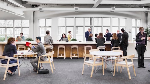 People mingle in a gathering place at Herman Miller's Design Yard. Select to go to an article and video about the transformation of this workplace.