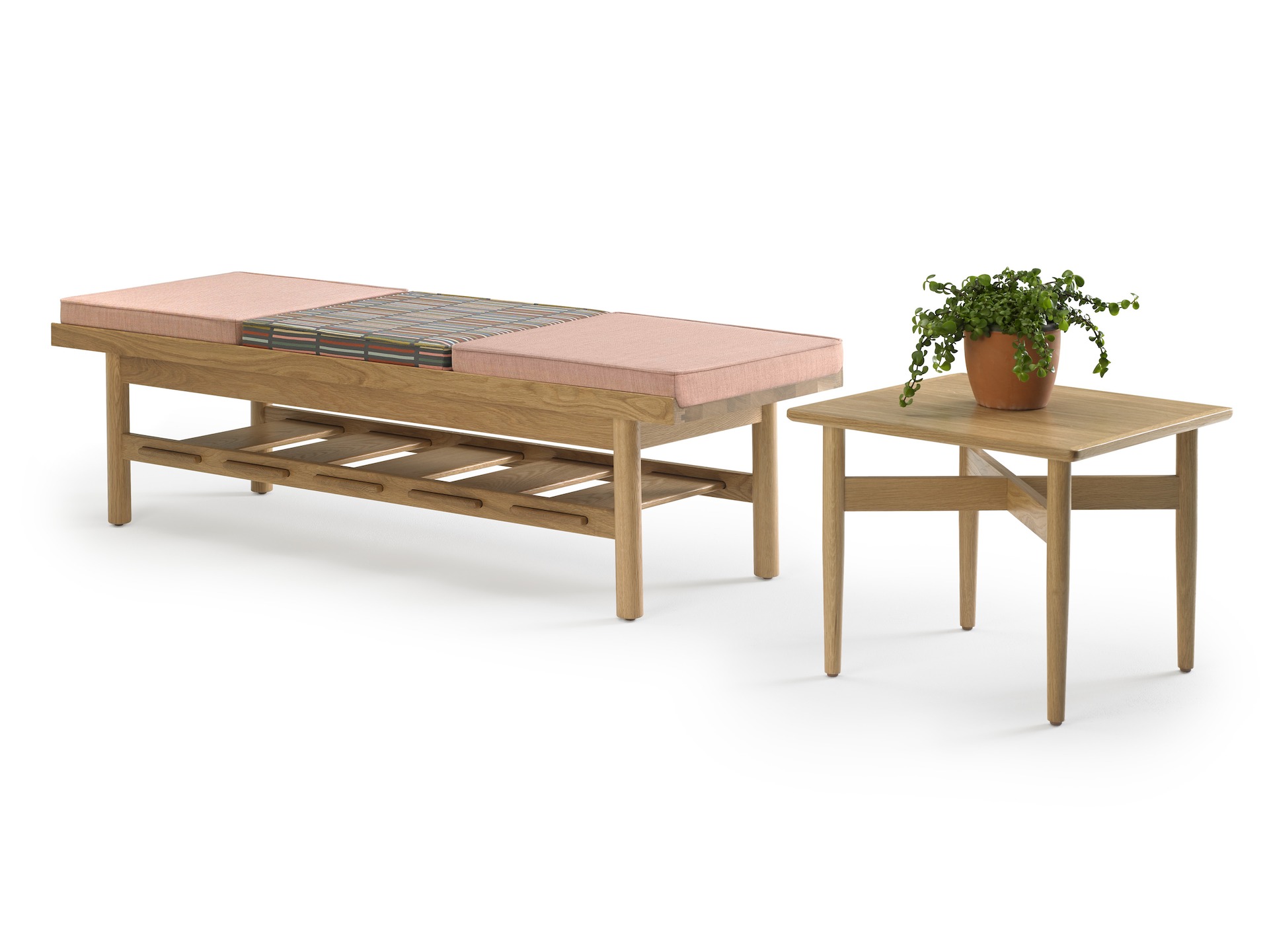 A square Hemlock side table with a potted plant on it and a Tamarack Table and Bench in maple topped with a pink cushion.