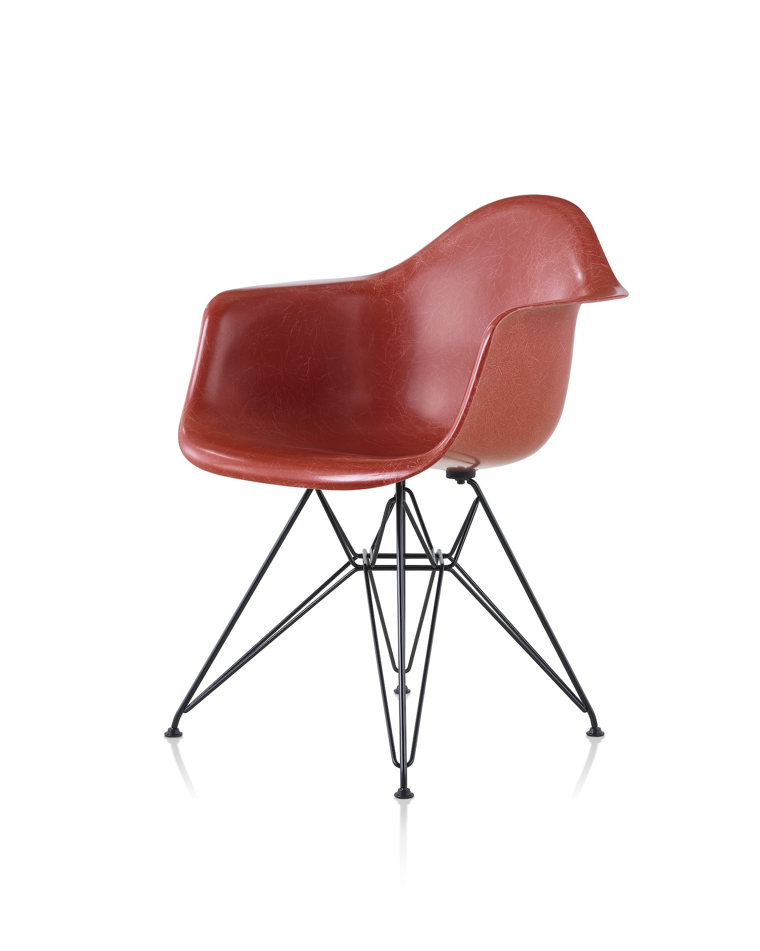 A red Eames Molded Fiberglass Chair with arms and a wire base, viewed at an angle.