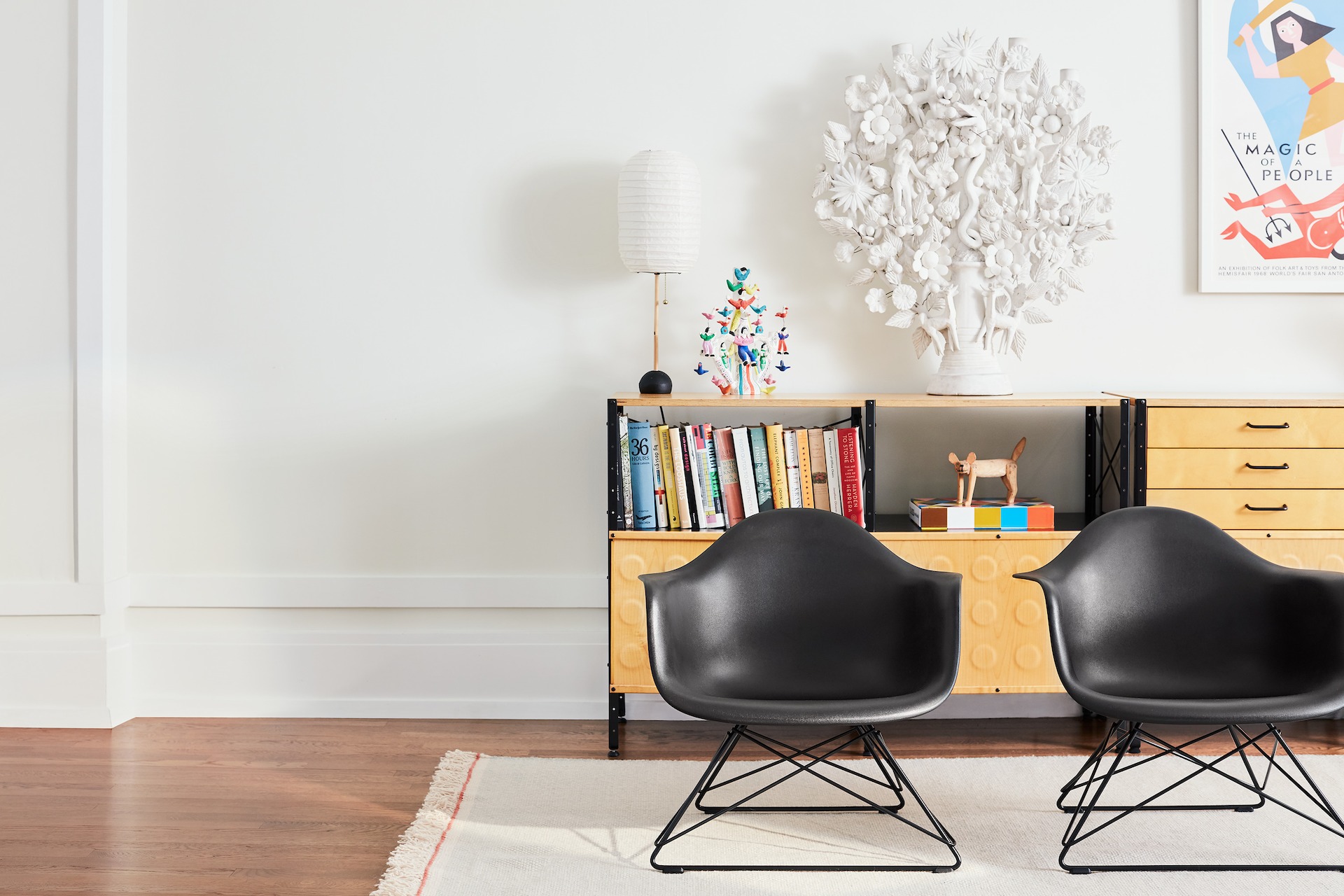 Two Eames Molded Plastic Armchairs with low wire bases in front of an Eames Storage Unit in a casual lounge setting.