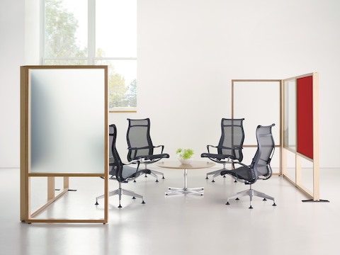 Four black Setu high-back office chairs surround a low Everywhere Table in a compact meeting space defined by two Canvas Group boundary screens.