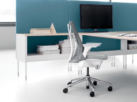 A small Public Office Landscape workstation with a peninsula surface, low storage, blue privacy screens, and a light gray Sayl Chair.