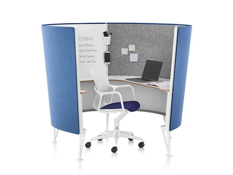 A white Keyn office chair with dark blue seat pad in a blue four-panel Prospect Solo Space containing a wraparound surface and whiteboard.