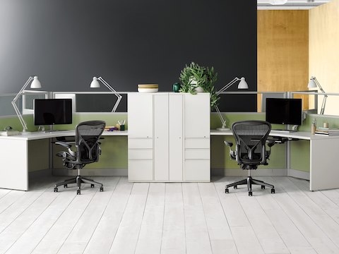 Two 120-degree Action Office System workstations with light green panels and white surfaces and storage, supported by black Aeron office chairs.