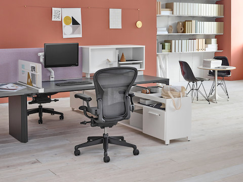 A Layout Studio workstation with a gray desk surface, white storage components, light purple privacy screen, and black Aeron office chair.