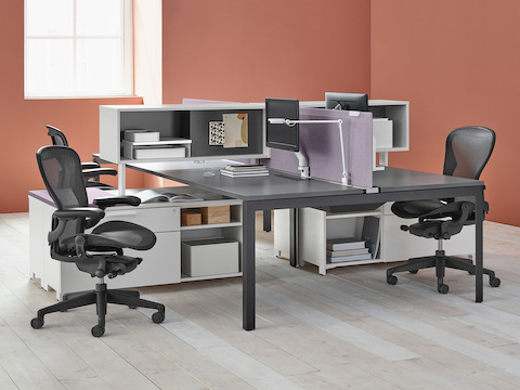 A cluster of Layout Studio workstations separated by desk-height storage components and light purple Pari privacy screens.