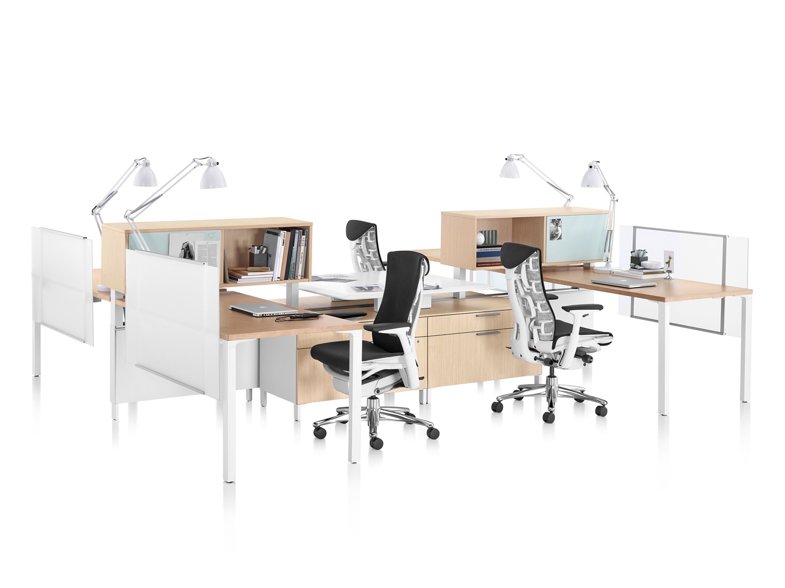 A cluster of four Canvas Office Landscape workstations with storage and surfaces in a light wood finish and black Embody office chairs.