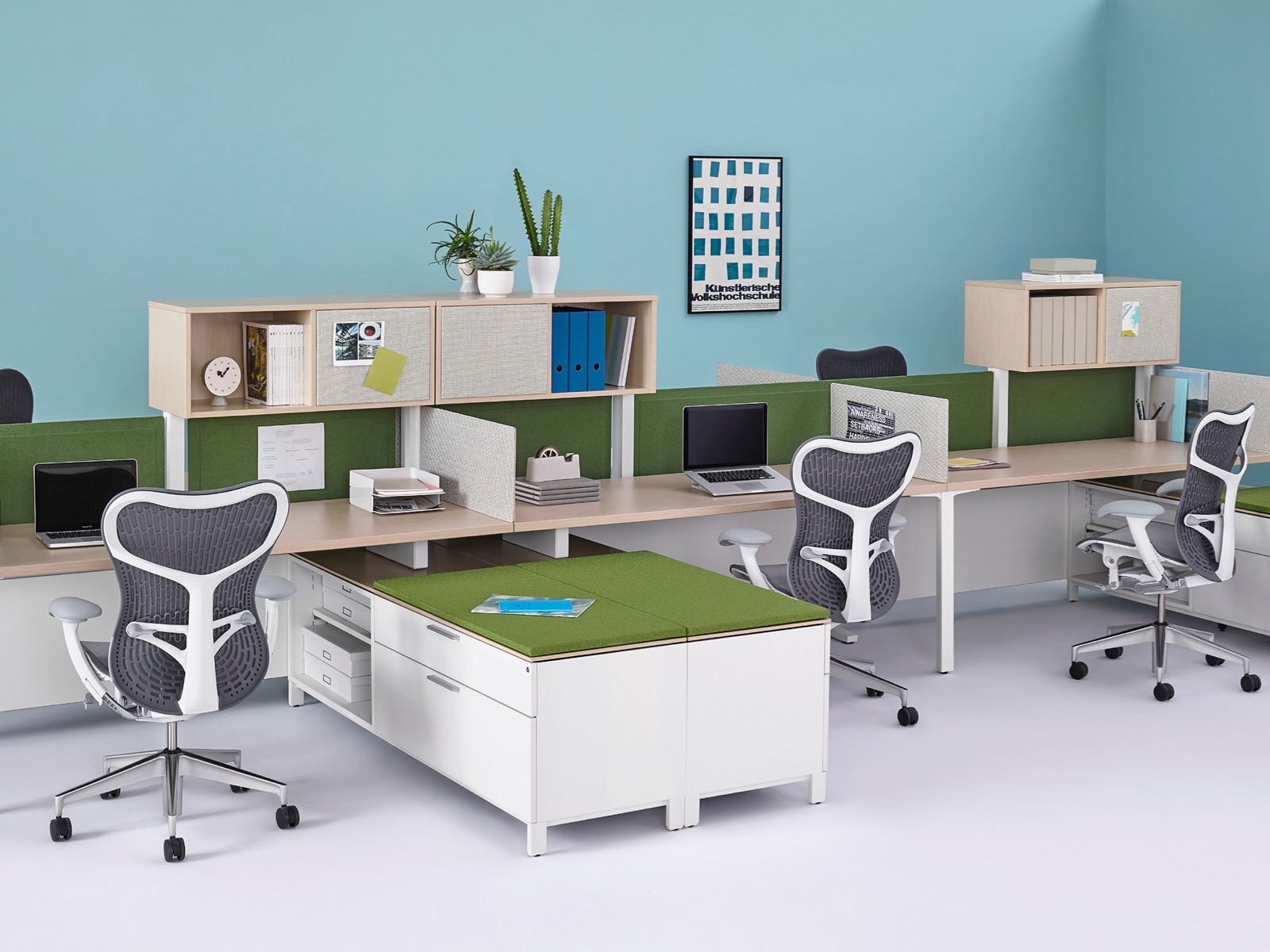 Canvas Dock workstations with surfaces and overheads in a light wood finish, green Pari privacy screens, and low storage with green cushioned tops.
