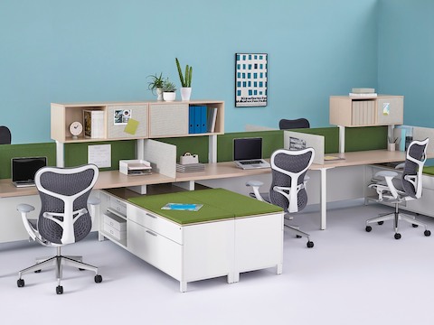 Canvas Dock workstations with surfaces and overheads in a light wood finish, green Pari privacy screens, and low storage with green cushioned tops.