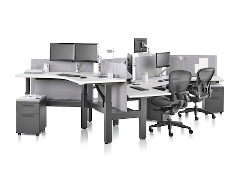 Standing desk system, Renew Link, with 120-degree work surfaces, Tu pedestals, and Aeron chairs. Two of the six desks are raised at a standing height.
