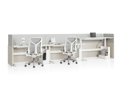Standing desk system, Renew Link, with rectangular work surfaces, privacy screens, and Cosm Chairs. One of three desks is raised to standing height.