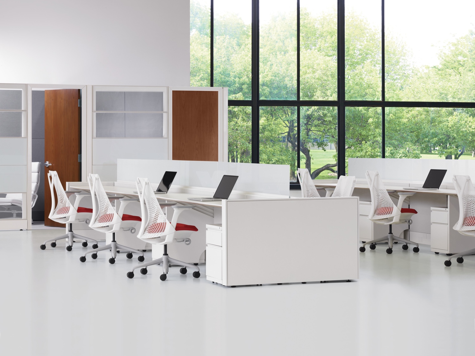 A mostly white workplace featuring two rows of the Ethospace System in a benching configuration, Tu storage pedestals, and Sayl office chairs.