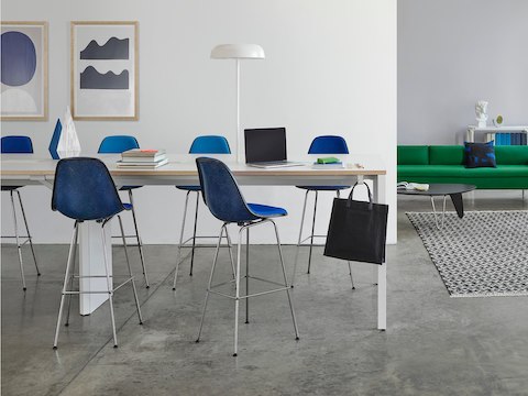 An interaction area with a Layout Studio meeting table offers a mix of seating, including a green Bolster Sofa and blue stools and side chairs.