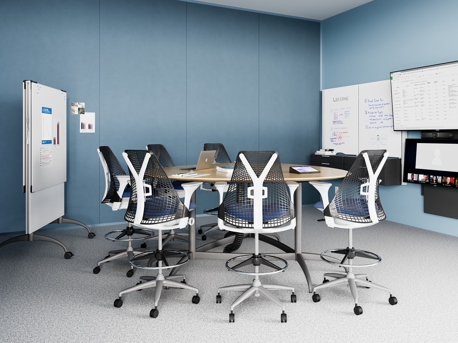 A light blue meeting space with a round table and Sayl Stools, featuring the technology from Logitech.