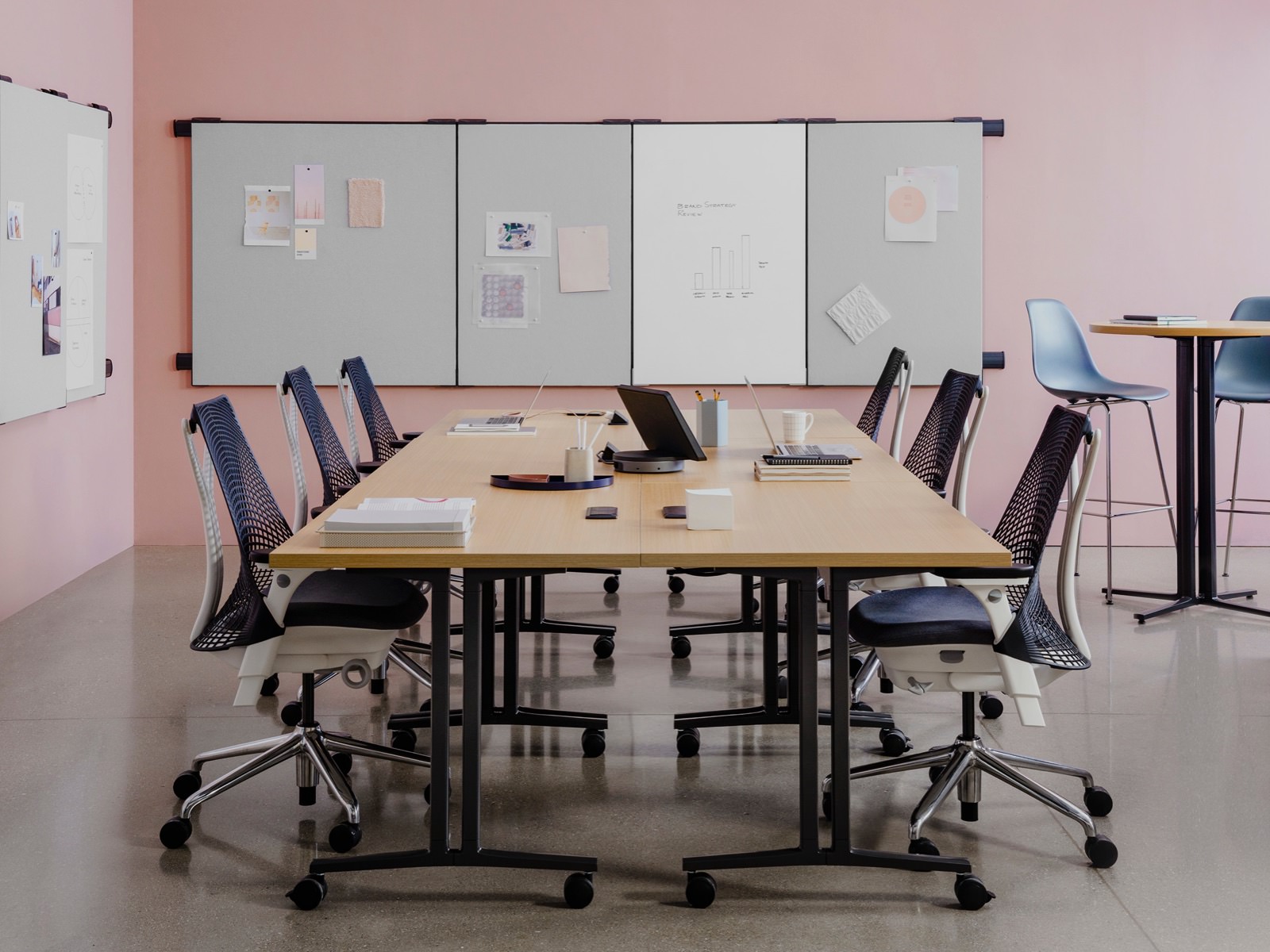 Meeting tables in a Workshop Setting with locker storage and project work pinned on boards attached to the walls.