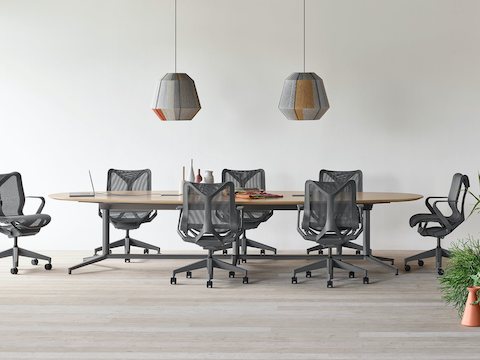 A Y base Headway conference table surrounded by seven Cosm chairs in an open conference space with a Headway communal table with Crosshatch stools nearby.