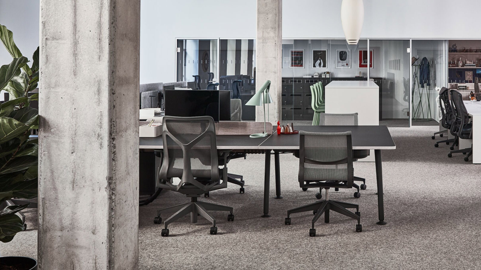 Ein Arbeitsplatz im Showroom in Paris mit Setu und Cosm Stühlen, die um einen schwarzen Memo Schreibtisch herum angeordnet sind.