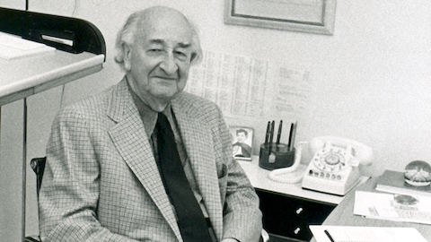 A portrait of D.J. De Pree sitting at a desk in an Eames Aluminium Group Chair.