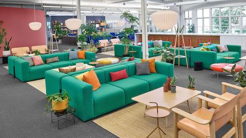 Conjunto de sofás Mags Soft de color verde frente a dos sillas en un esquema de plaza colaborativo.