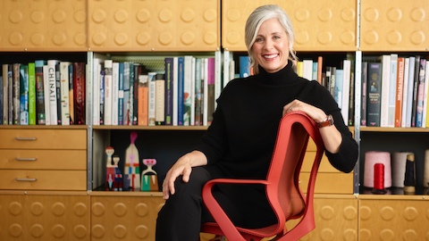 Andi Owen, President and CEO of Herman Miller, sits in a red Cosm Chair.