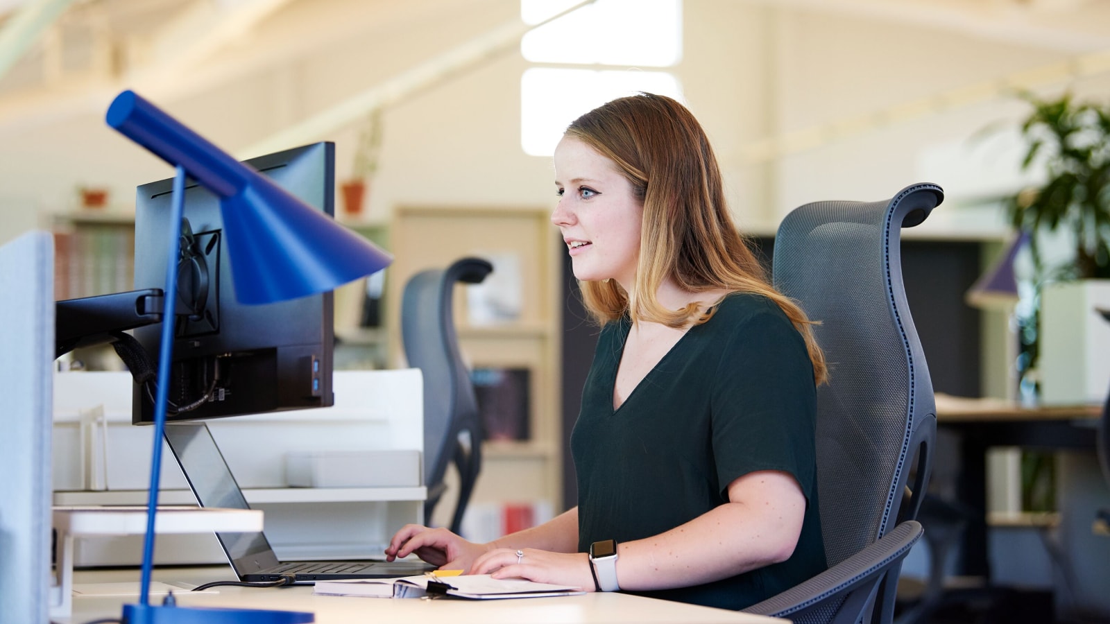 A young women sitting at a desk working on a computer. A young women sitting at a desk working on a computer.