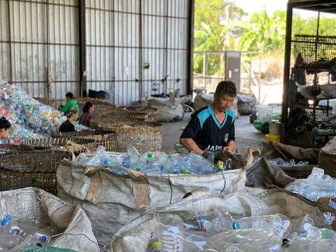 Ein Mann in einem Lagergebäude sortiert Plastikflaschen.