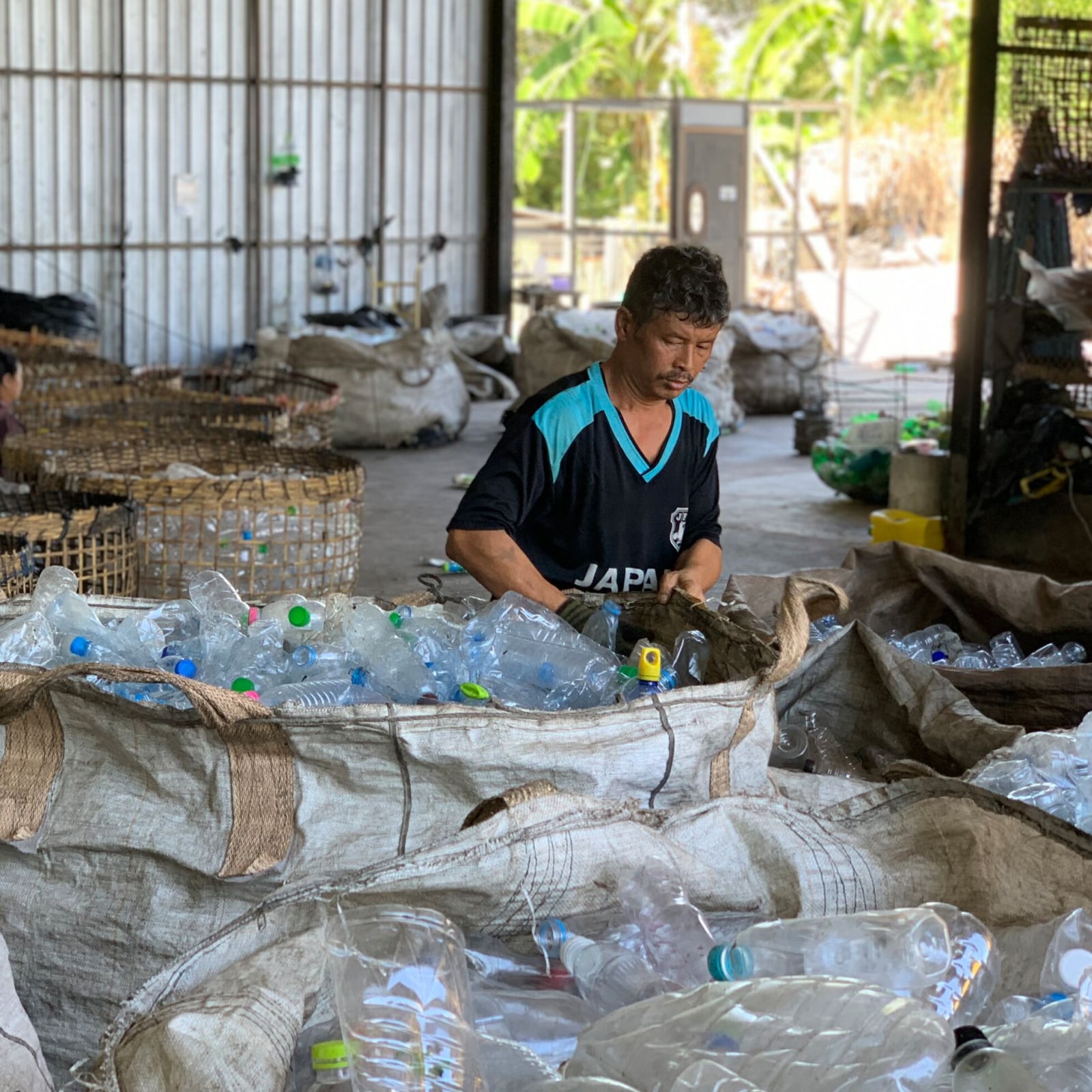 A man sorting plastic bottles in a warehouse. 