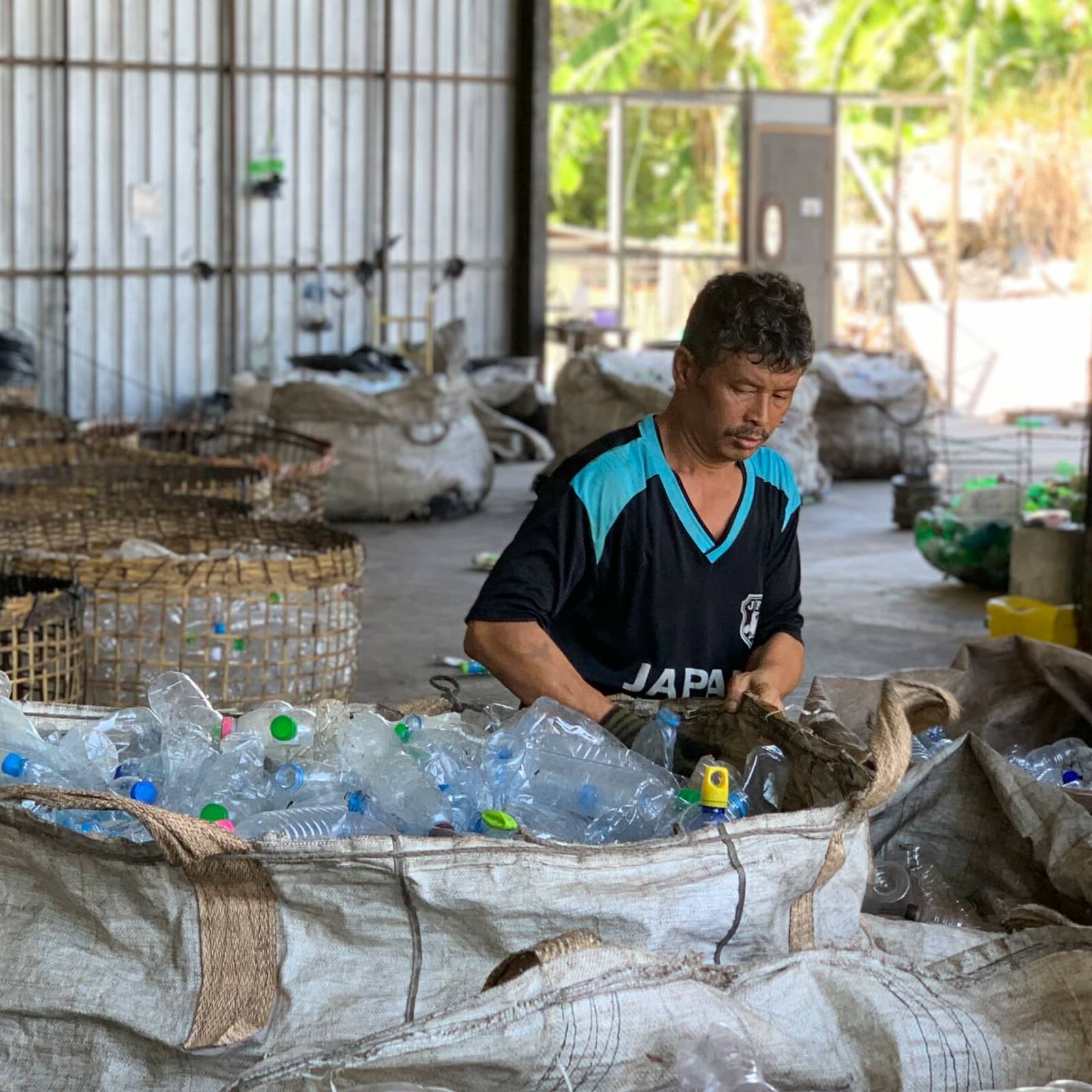 Ein Mann in einem Lagergebäude sortiert Plastikflaschen.