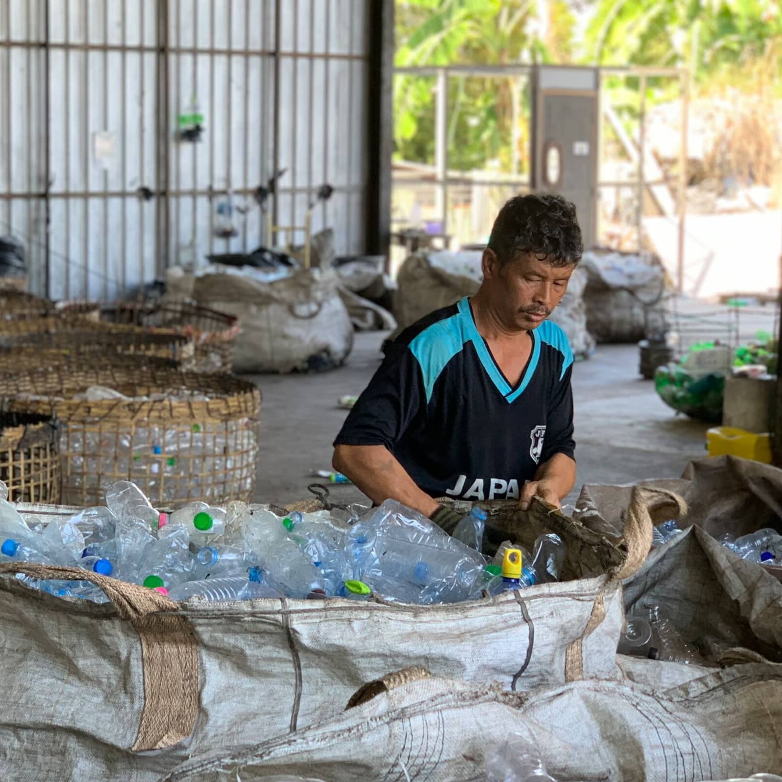 A man sorting plastic bottles in a warehouse.