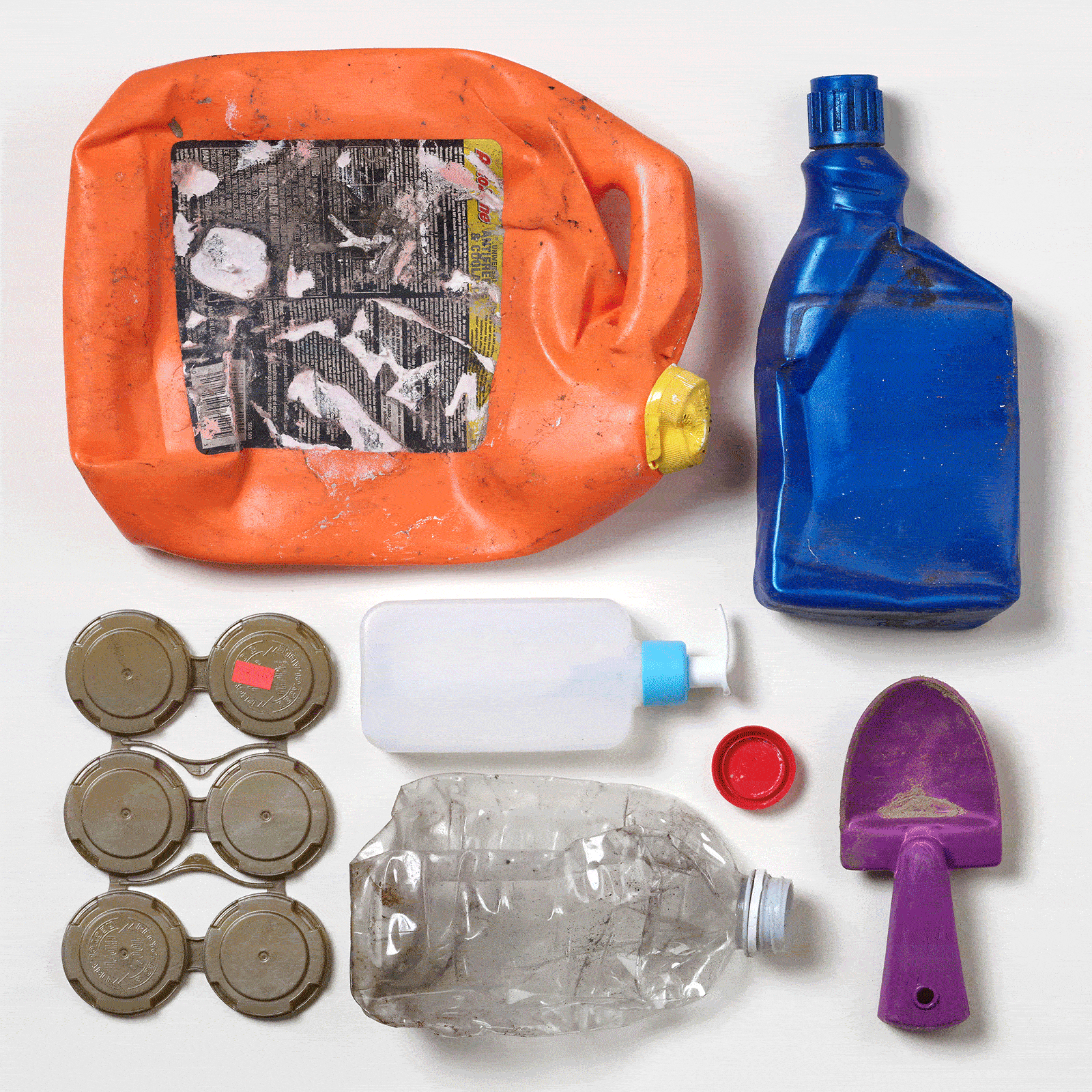 Siete piezas de residuos plásticos coloridos y recuperados del océano dispuestos en un patrón cuadrado sobre un fondo blanco.