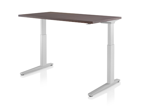 A Renew standing desk with light gray legs and dark wood work surface raised to standing height.