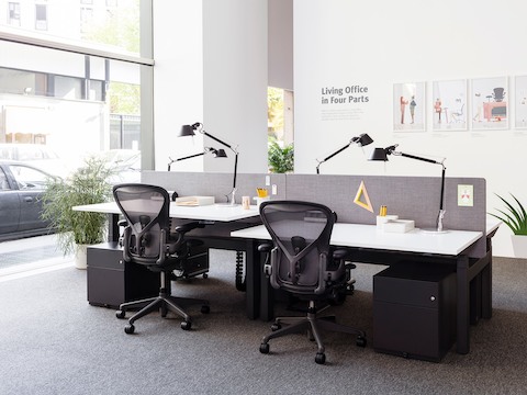 Dos puntos de trabajo en una configuración benching, con escritorios y sillas para oficinas Aeron en negro, posicionadas a diferente altura.