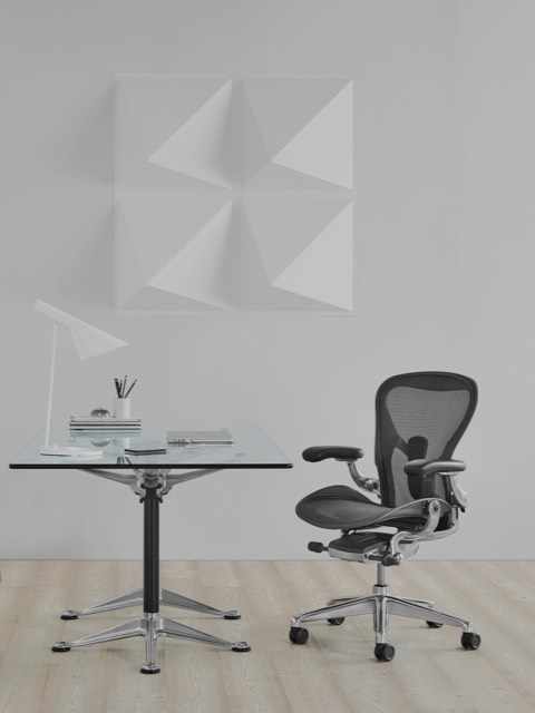 A square Burdick table with a glass top, used as a desk and complemented by a black Aeron office chair. A square Burdick table with a glass top, used as a desk and complemented by a black Aeron office chair.