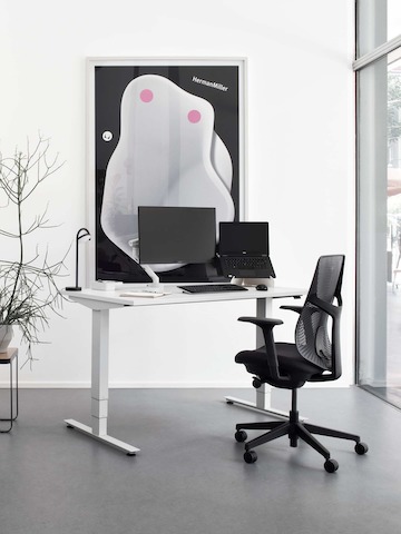 Ein einzelner höhenverstellbarer Nevi Schreibtisch und ein schwarzer Verus Stuhl.