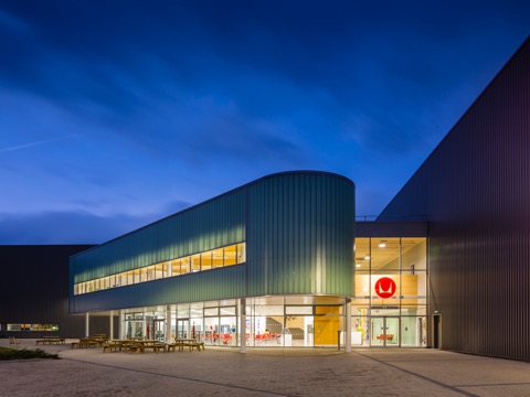 A night photo of the exterior of a Herman Miller manufacturing facility in the UK.