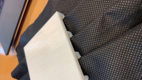 A close-up image of a plastic guide for creating the folds in a face mask. 