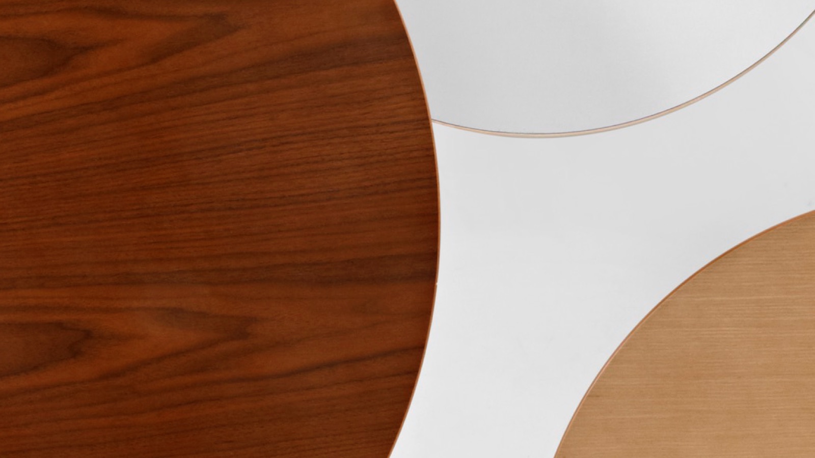 Layered tabletops in a variety of materials including walnut veneer, white laminate, and ash veneer.
