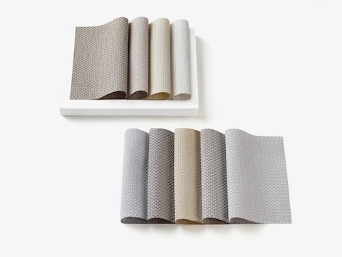 Multiple folded 100% recycled content fabric swatches in calming, neutral colors.