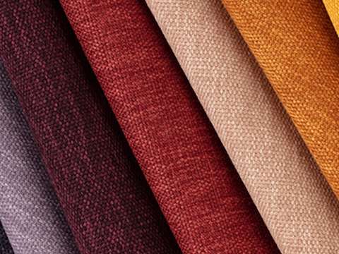 Multiple folded Metaphor fabric swatches in varying colours including orange, red and purple.
