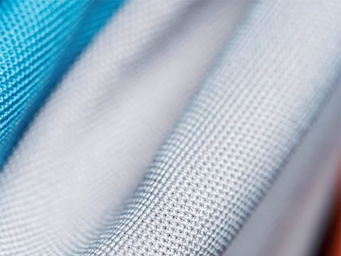 Plusieurs échantillons de tissu Sprint pliés dans différentes couleurs, dont des bleus et des gris.