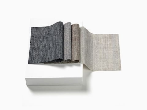 Deux piles d'échantillons de tissus Terra 100 % recyclés dans des couleurs texturées et neutres.