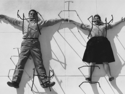 A vintage photo of Charles and Ray Eames holding hands in a playful posture.