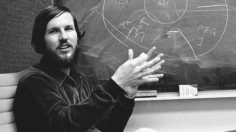 Product designer Tom Newhouse gestures before a chalkboard.