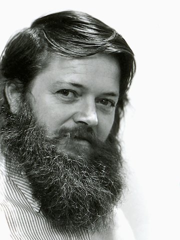 Um retrato em preto-e-branco do designer Ray Wilkes. Visto em um ângulo frontal em três quartos.