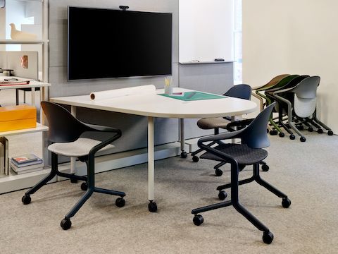 Fuld Nesting Chairs shown at a table and nested against the wall