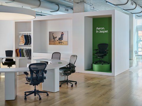 Two Aeron ergonomic office chairs in midnight blue and an earthy green at an oval conference table.