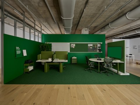 Two small OE1 workstations, OE1 D-shaped huddle table, and three green Aeron chairs in a green room.